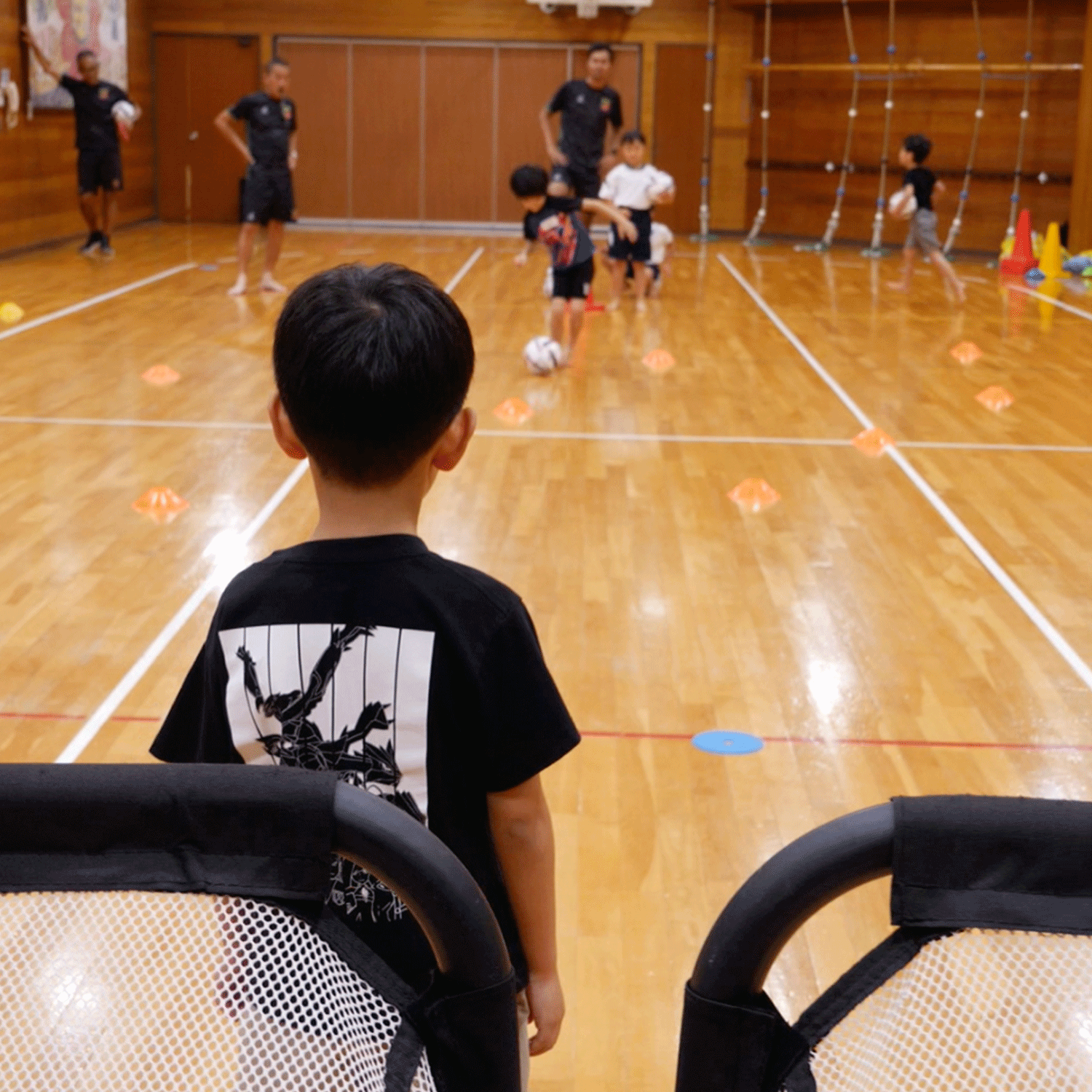 サッカーのゴールを狙う子供と守る子供の背中
