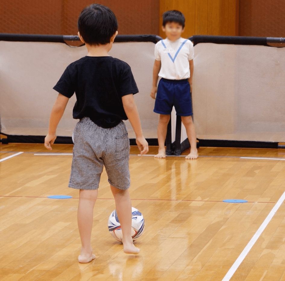 サッカーのゴールを狙う子供と守る子供