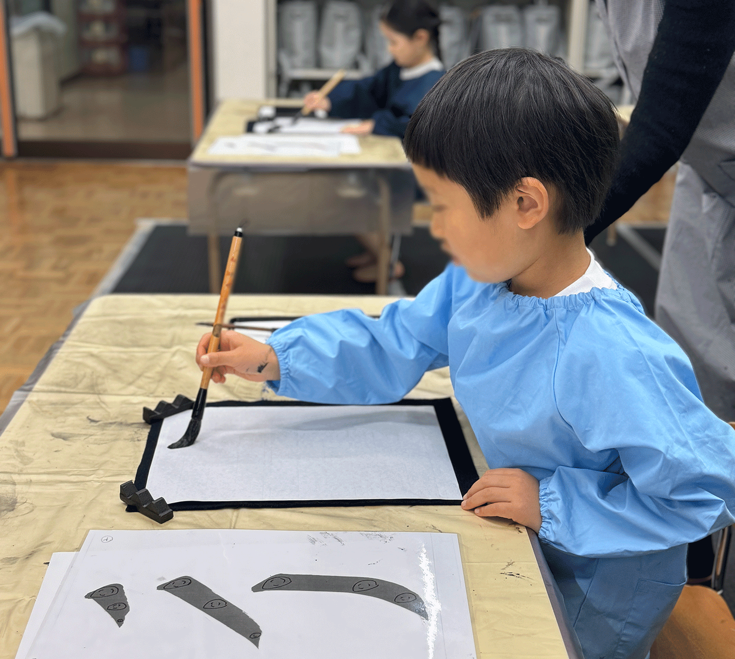 姿勢よく座って書道をする子ども