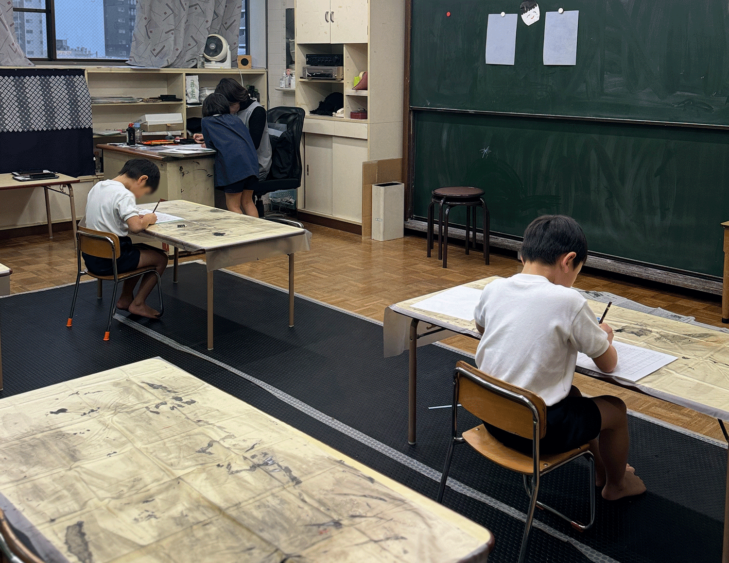 教室で書道に取り組む3人の子ども