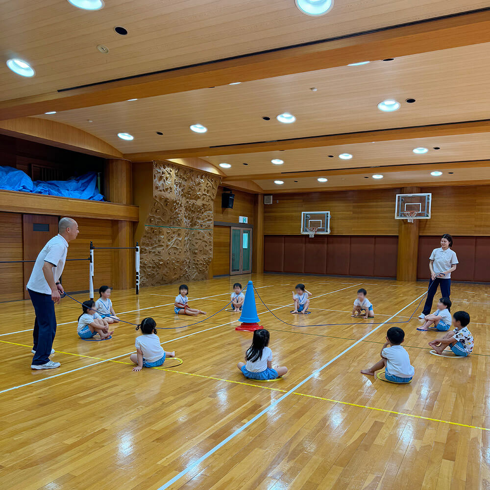円になって講師が回す大縄を飛び越えるゲームをする子どもたち
