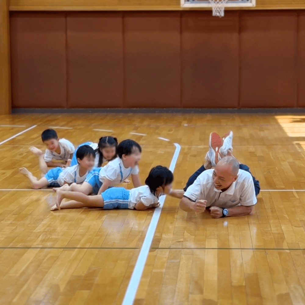 ワニの真似をして匍匐前進をする子どもたちと講師