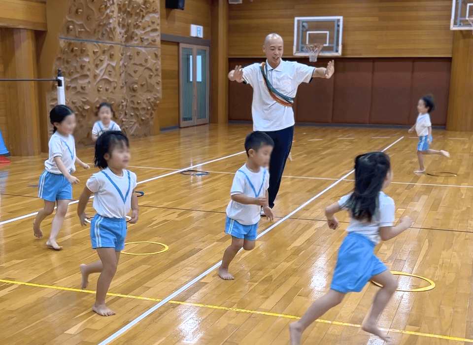 フープ取りゲームで追いかけてくる講師から逃げる子どもたち