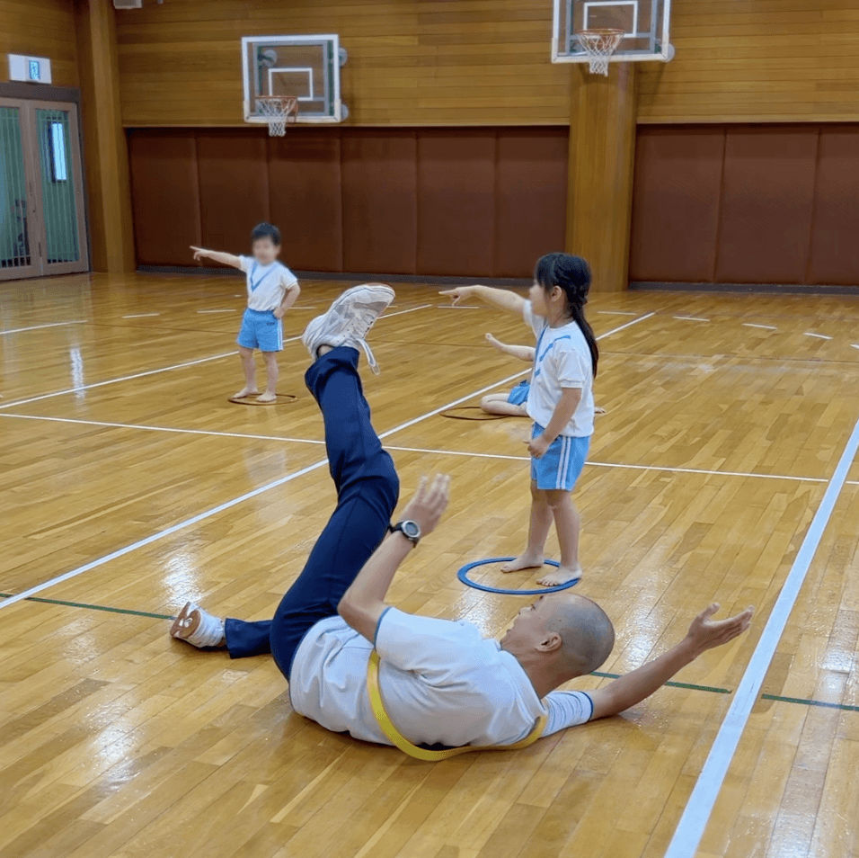 フープ取りゲームで子どもを捕まえようとする講師