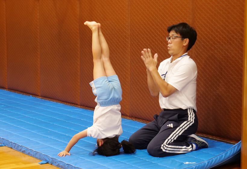 三点倒立に挑戦する子どもと拍手で励ます講師｜パドマ幼稚園体操教室