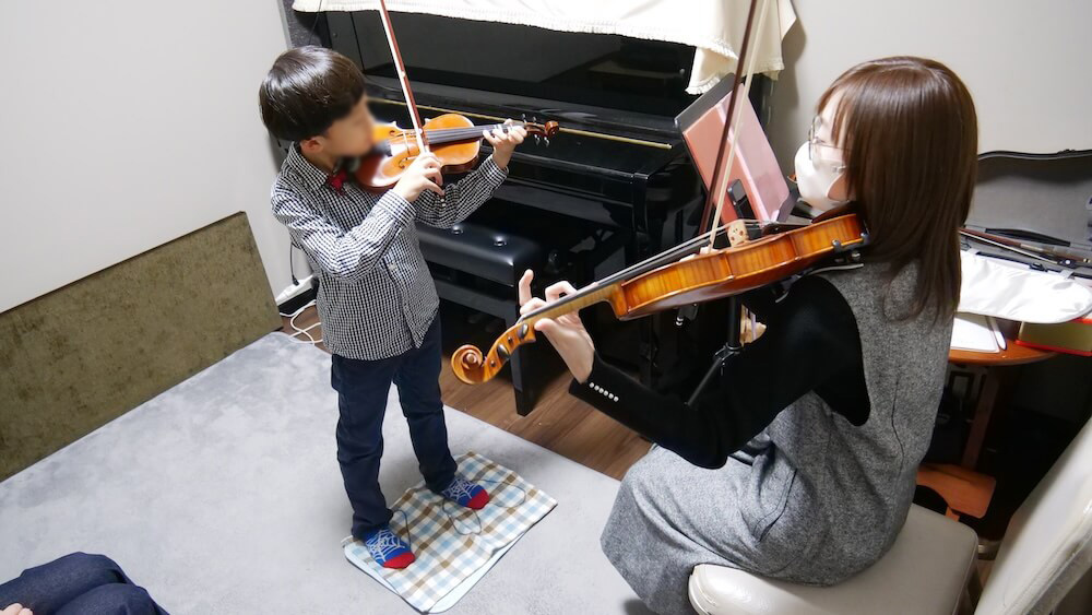 向かい合ってバイオリンを弾く子どもと講師