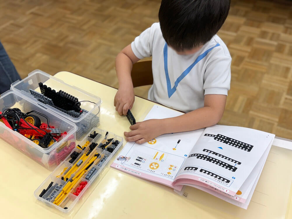 テキストを見ながら真剣にロボットを組み立てる子ども