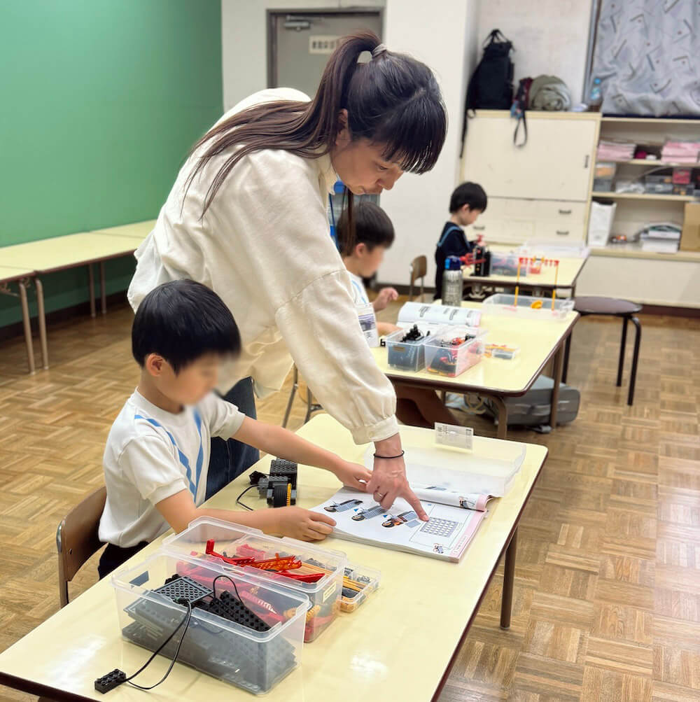 テキストを指差して子どもにヒントを伝える講師